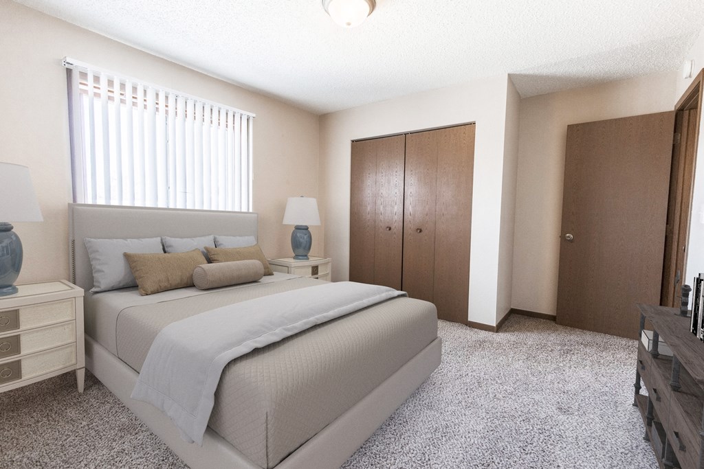 Grand Forks, ND Sunview apartments.  a bedroom with a bed and two nightstands with a closet and a window