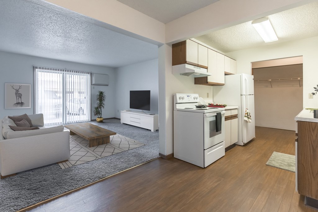 Grand Forks, ND Sunview apartments.  a living room with a couch, coffee table, tv, and a glass sliding door. A kitchen to the right