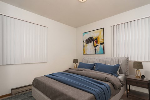 Grand Forks, ND Valley Home Duplex. a bedroom with two windows and a bed with a gray blanket and blue pillows