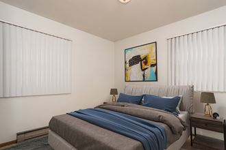 Grand Forks, ND Valley Home Duplex. a bedroom with two windows and a bed with a gray blanket and blue pillows - Photo Gallery 5