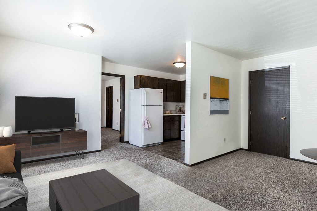 a living room with a tv and a kitchen in the background