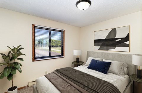 a bedroom with a bed and a window and a plant. Hutchinson, MN Echo Manor Apartments