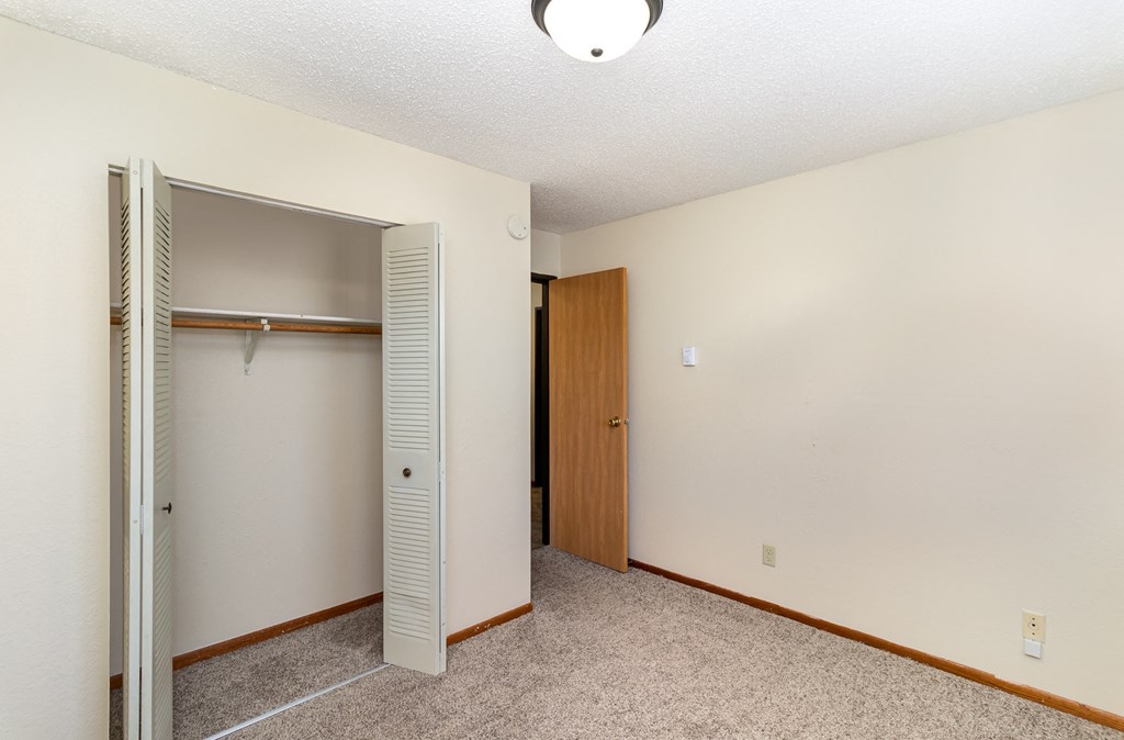 a bedroom with a closet and an open door. Hutchinson, MN Echo Manor Apartments