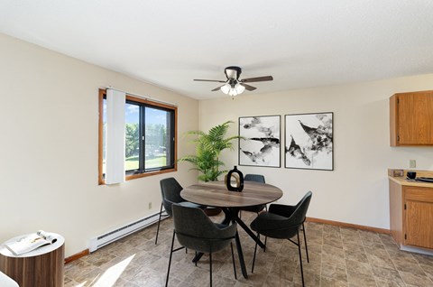 a dining room with a table and chairs and a ceiling fan. Hutchinson, MN Echo Manor Apartments
