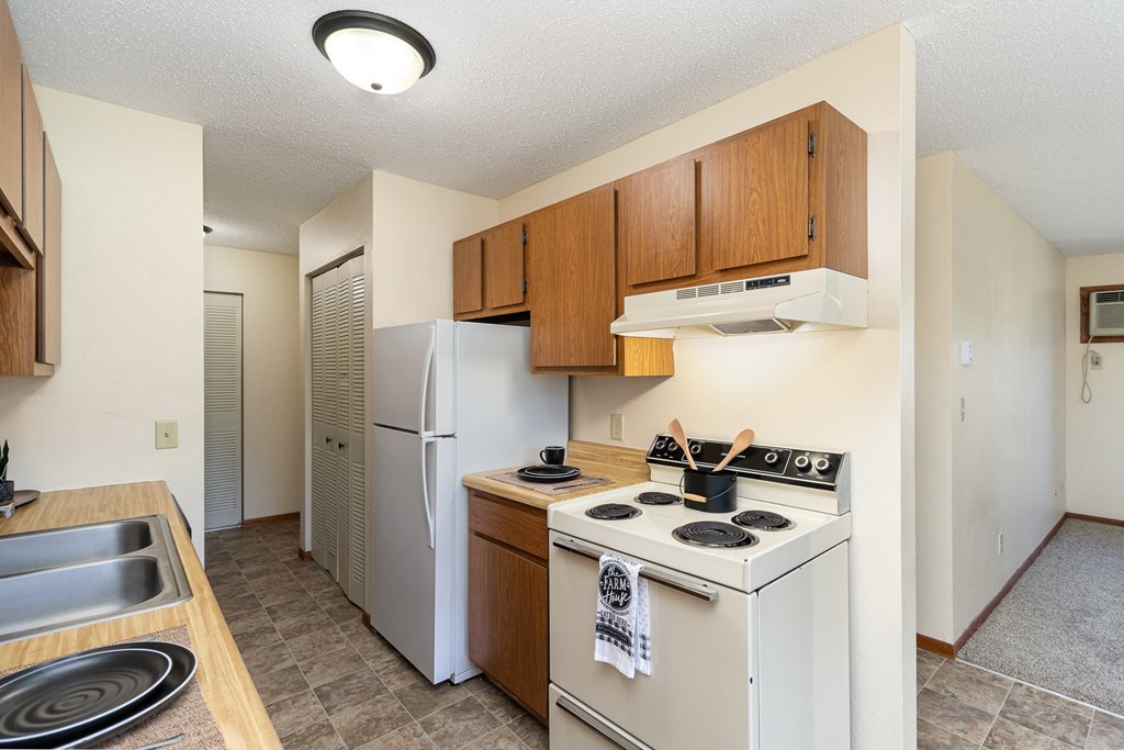 a kitchen with white appliances and wooden cabinets and a white refrigerator. Hutchinson, MN Echo Manor Apartments
