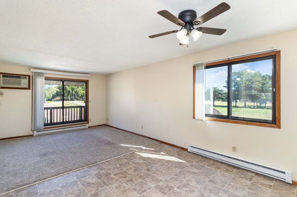 an empty living room with a ceiling fan and a window. Hutchinson, MN Echo Manor Apartments