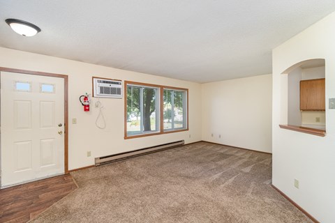 an empty living room with a white door and a window. Hutchinson, MN Twin Oaks Townhomes