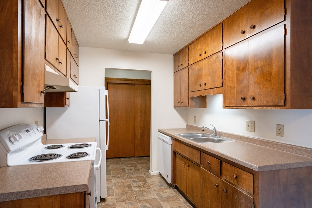 a kitchen with a stove and sink and a refrigerator. Fargo, ND Betty Ann Apartments