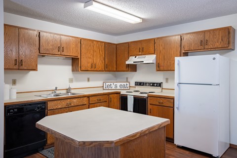 a kitchen with wooden cabinets and white counters and a refrigerator