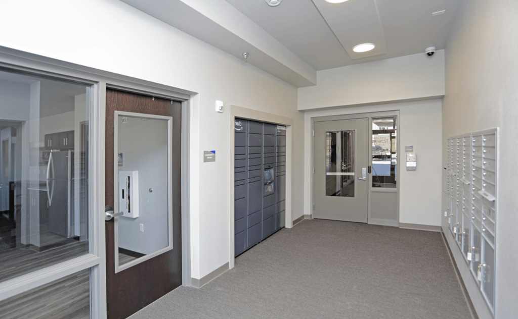 A hallway with a white wall and a brown door. Fargo, ND 29 West Apartments