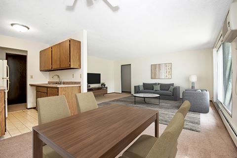 A dining area in Maplewood Apartments 21B. The room has a 4 chair table with the living room in the background