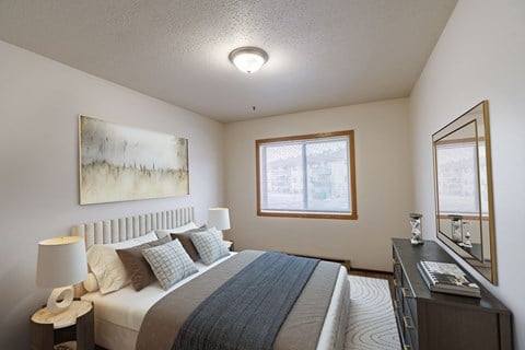 a bedroom with a bed and a dresser and a window. Moorhead, MN South Park Apartments