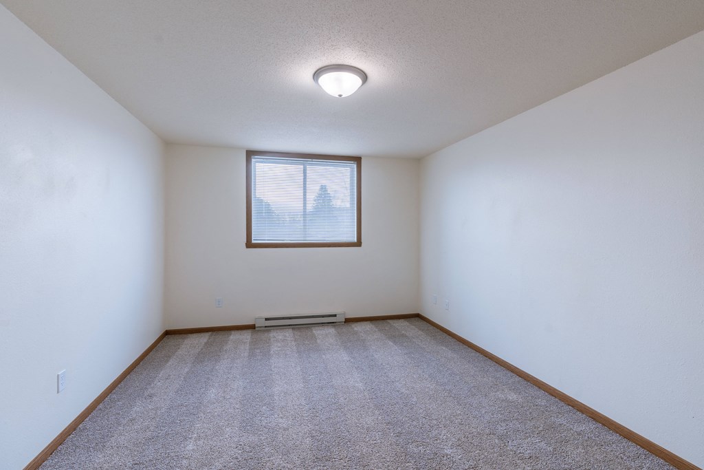 a bedroom with a window and carpet. Moorhead, MN South Park Apartments