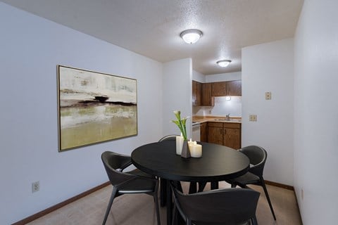a dining room with a table and chairs and a kitchen. Moorhead, MN South Park Apartments