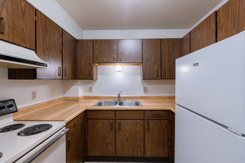 an empty kitchen with white appliances and wooden cabinets. Moorhead, MN South Park Apartments