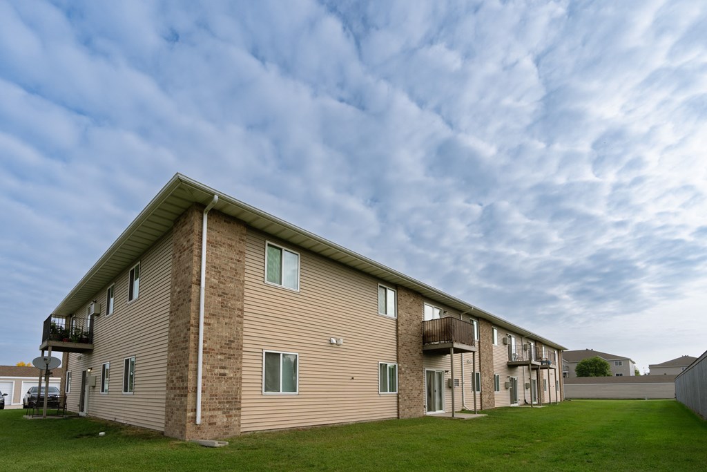 an apartment building with a cloudy sky in the background. Moorhead, MN Woodstone Apartments