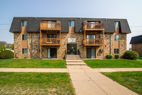 an apartment building on a sunny day with a sidewalk in front of it