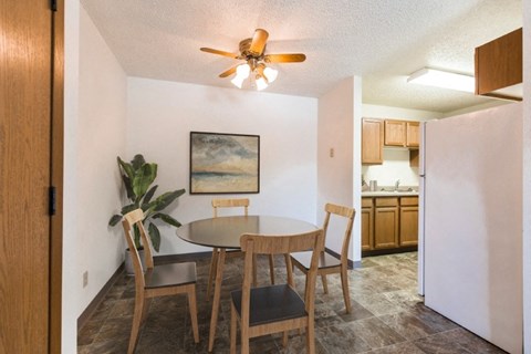 a dining area with a table and chairs and a kitchen in the background