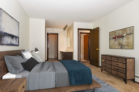 A cozy master bedroom in Sage Park, New Brighton. The room showcases a comfortable bed with inviting bedding and minimalistic decor, with a large dresser.