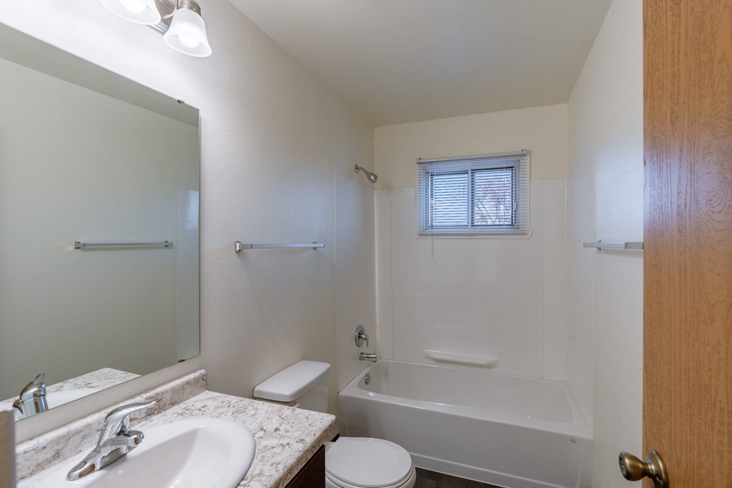 a bathroom with a sink toilet and bath tub and a mirror. Fargo, ND North Manor Apartments