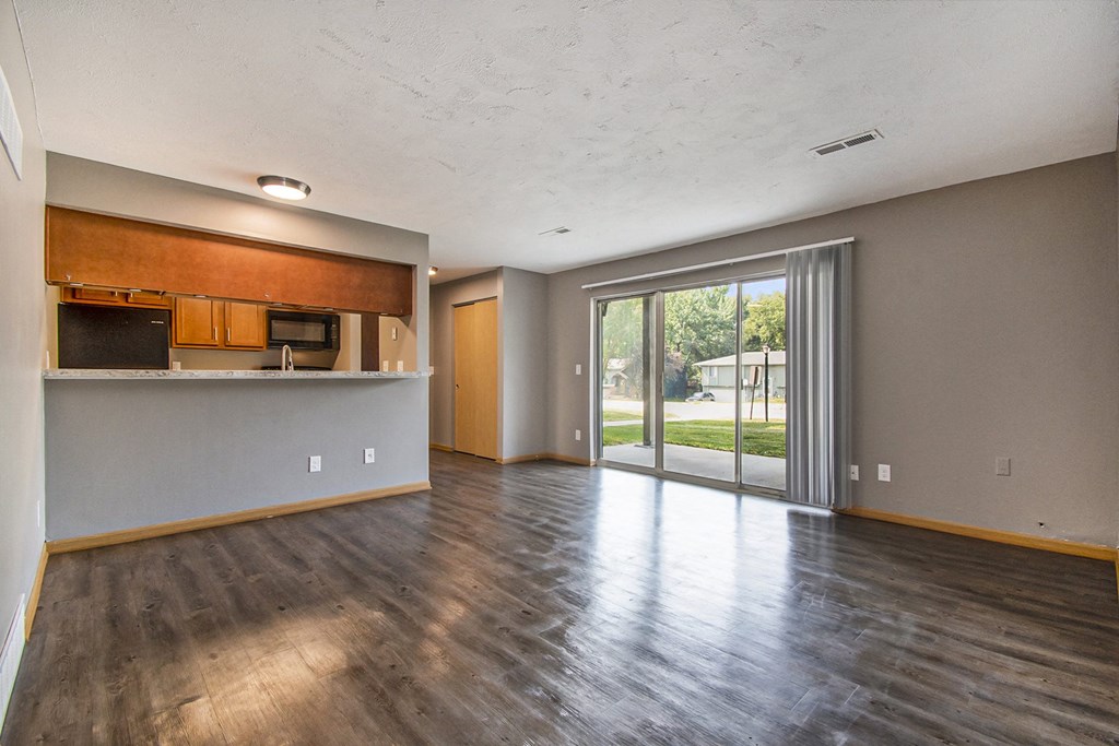 Omaha, NE Beacon Hill Apartments. An empty living room with a sliding glass door leading to a patio