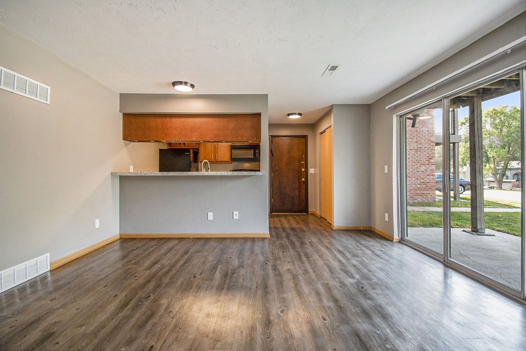 Omaha, NE Beacon Hill Apartments. A living room with a glass sliding door and a kitchen in the background