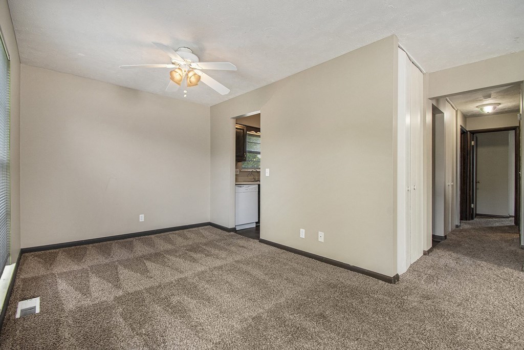 Omaha, NE Beacon Hill Apartments. An empty living room with a ceiling fan and a kitchen in the background