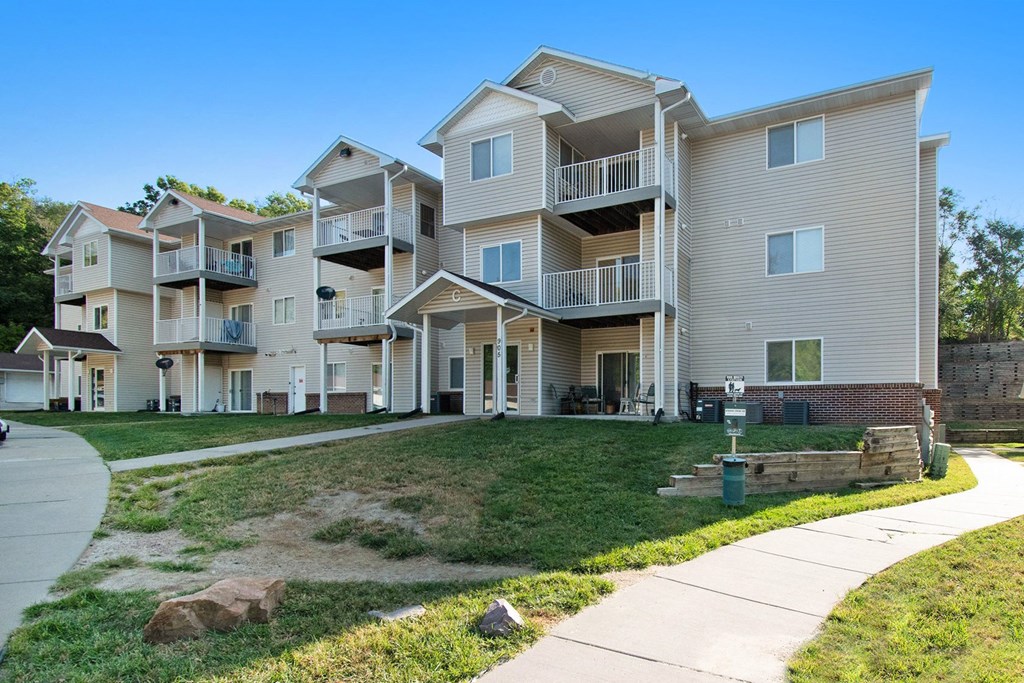 Omaha, NE Deerfield Apartments | Exterior Omaha, NE Deerfield Apartments. An exterior view of an apartment complex with a sidewalk in front of it