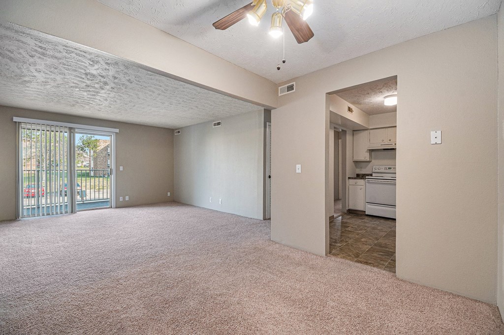 Omaha, NE Evergreen Terrace Apartments. A living room with a ceiling fan and a kitchen in the background
