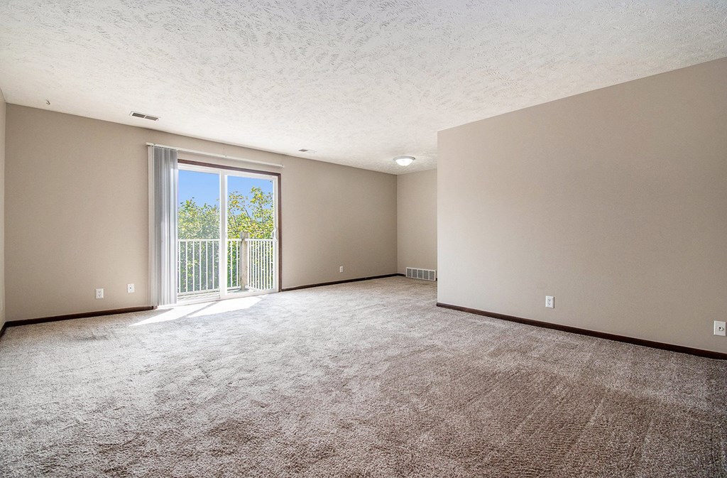 Omaha, NE Maple Ridge Apartments. A living room with a sliding glass door leading to a balcony