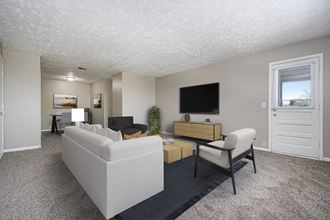 Omaha, NE Maple Ridge Apartments. A living room with white couches and chairs and a tv on the wall - Photo Gallery 2