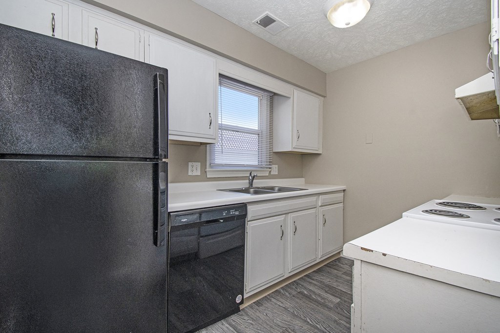Omaha, NE Maple Ridge Apartments. A kitchen with white cabinets and black appliances
