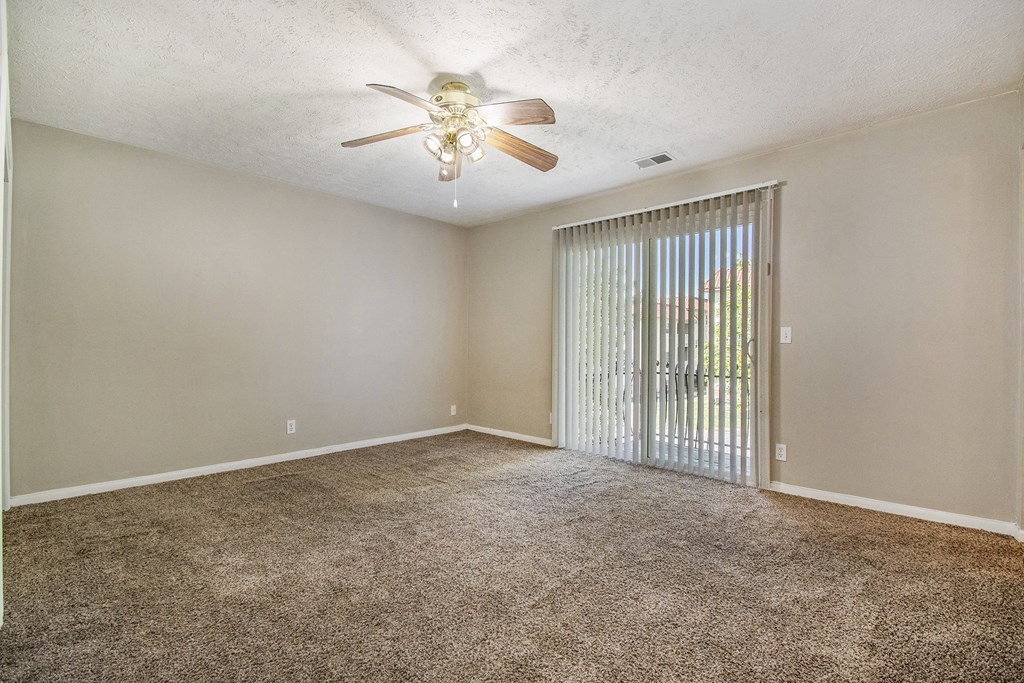 Omaha, NE Maple Ridge Apartments. A bedroom with a ceiling fan and a sliding glass door