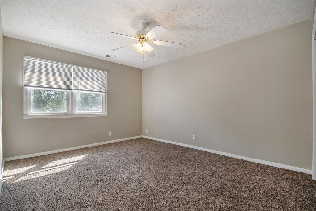 Omaha, NE Maple Ridge Apartments. A bedroom with a ceiling fan and two windows