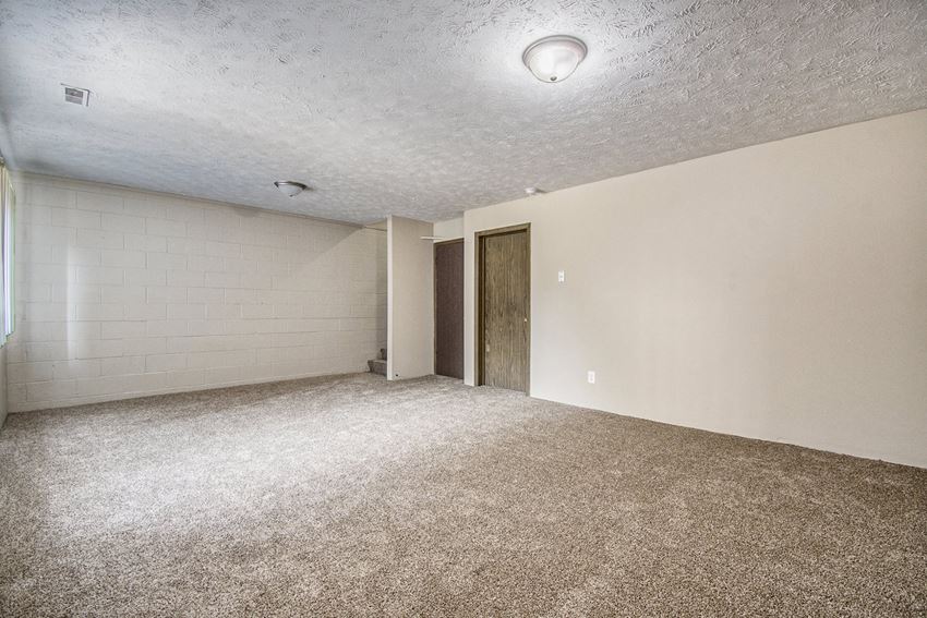 Omaha, NE Stony Brook Townhomes | Basement Omaha, NE Stony Brook Townhomes. A spacious living room with carpeted flooring and white walls