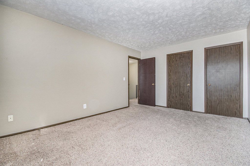 Omaha, NE Stony Brook Townhomes. A bedroom with two doors and a carpeted floor