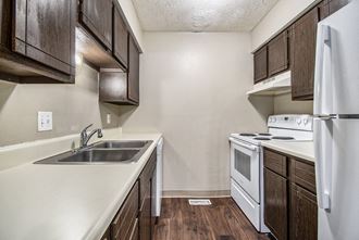 Omaha, NE Stony Brook Townhomes. A kitchen with white appliances and dark wood cabinets - Photo Gallery 5
