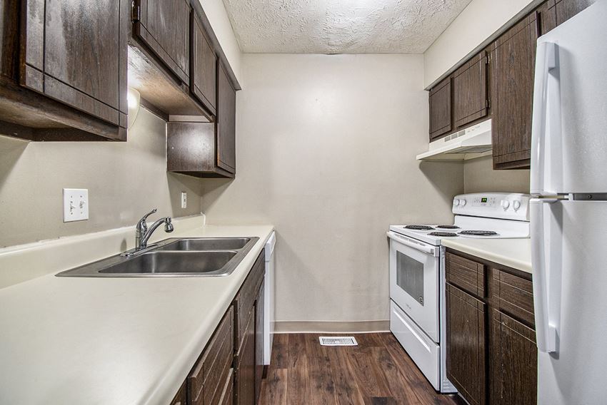 Omaha, NE Stony Brook Townhomes | Kitchen Omaha, NE Stony Brook Townhomes. A kitchen with white appliances and dark wood cabinets