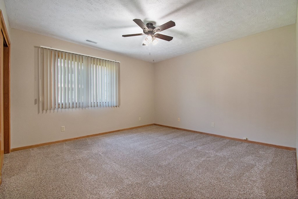 a bedroom with a ceiling fan and a window. Omaha, NE Woodland Pines Apartments