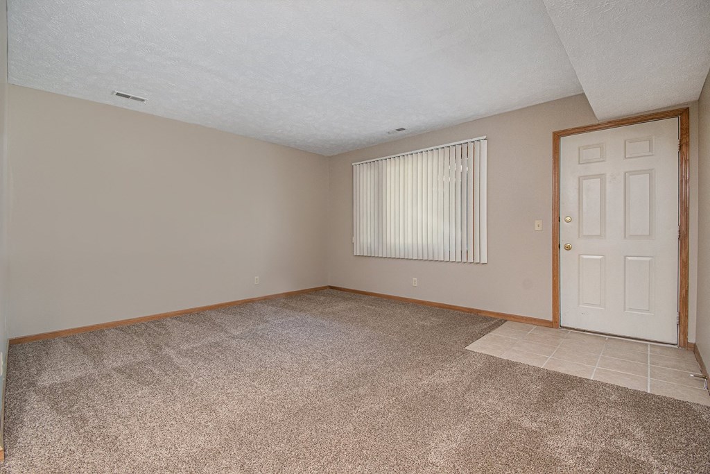 an empty living room with an exterior door. Omaha, NE Woodland Pines Apartments