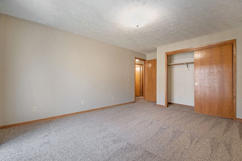 Omaha, NE Woodland Pines Apartments. A bedroom with a closet and a door to a bathroom