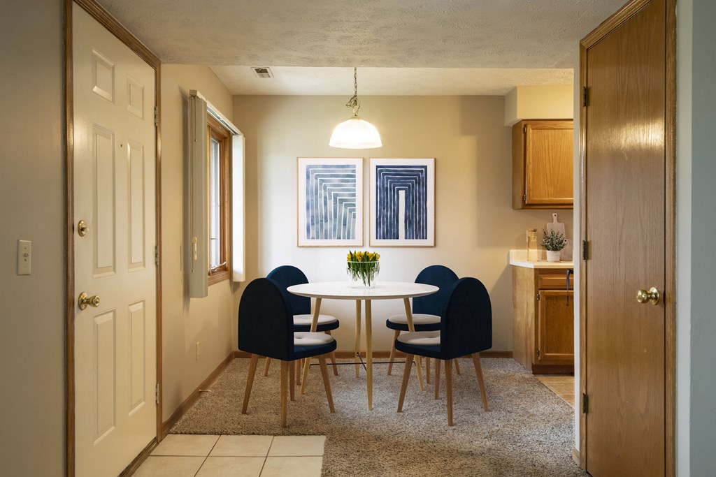 a dining room with a white table and blue chairs  at Woodland Pines, Omaha