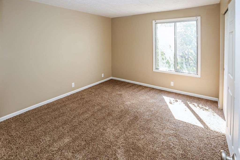 an empty room with carpet and a window. Omaha, NE Evergreen Terrace Apartments