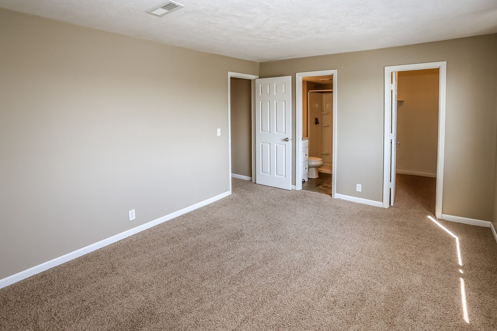 an empty living room with carpet and a door to a bathroom. Omaha, NE Evergreen Terrace Apartments