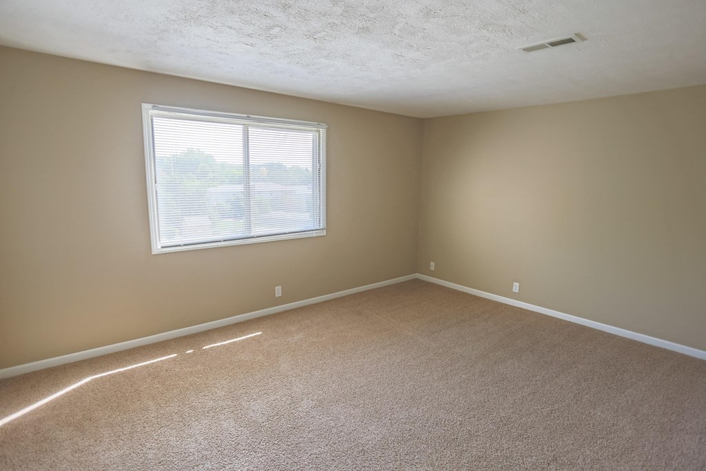 an empty living room with a window and carpet. Omaha, NE Evergreen Terrace Apartments