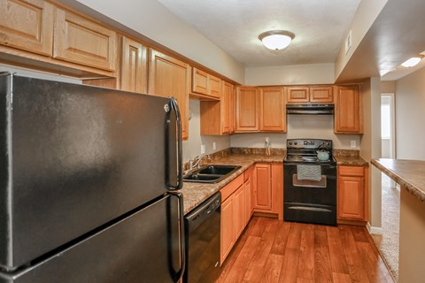 a kitchen with wooden cabinets and appliances and a black refrigerator