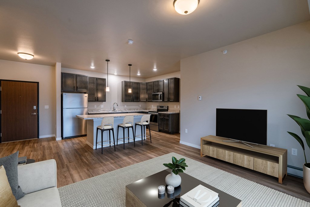 a living room with a kitchen and a tv in it. Fargo, ND Prairiewood Meadows Apartments