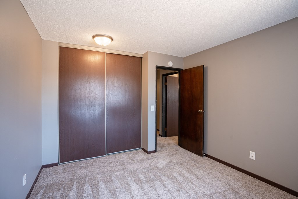 a bedroom with a closet and a door to a hallway. Roseville, MN Rosedale Estates Apartments
