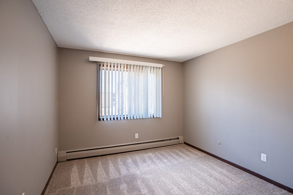 an empty room with a window and a carpeted floor. Roseville, MN Rosedale Estates Apartments