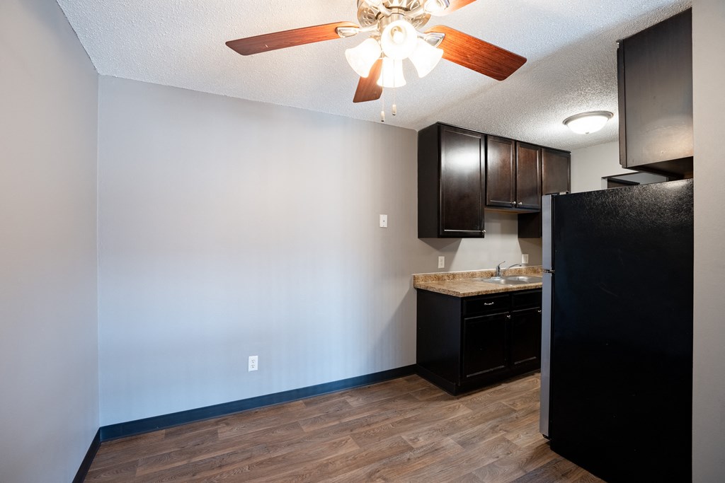 an empty kitchen with a ceiling fan and dark cabinets. Roseville, MN Rosedale Estates Apartments